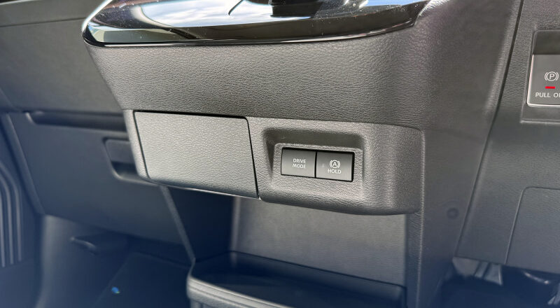 Dashboard area with a small two-button panel labeled DRIVE MODE and HOLD beside a storage compartment.