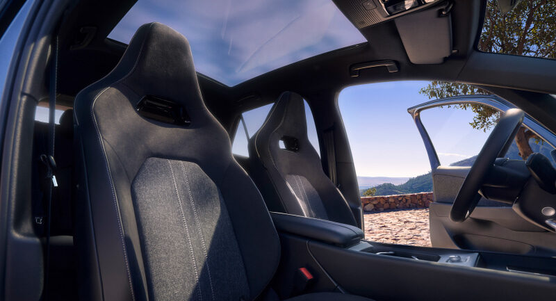 Front sport seats inside a modern car with an open door and a scenic landscape outside the window side viewailable moment