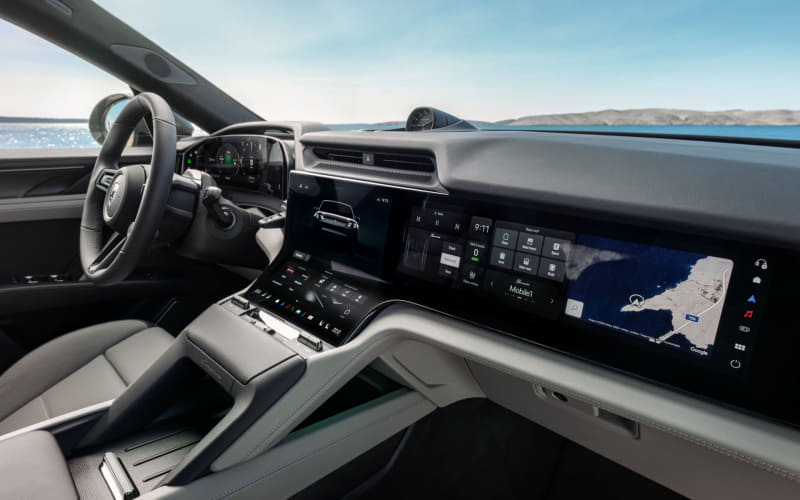 Modern car interior with steering wheel, digital dashboard, and a wide infotainment touchscreen showing a map on the right side.