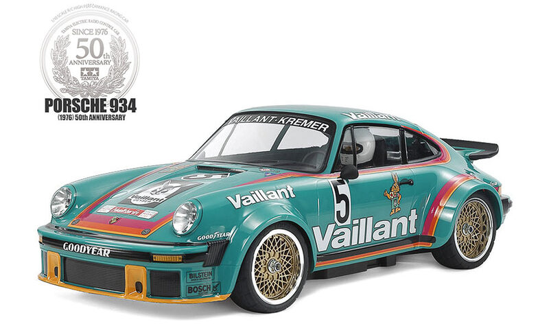 Teal Porsche 934 race car with Vaillant livery, number 5, gold wheels, commemorating Porsche 50th anniversary logo nearby