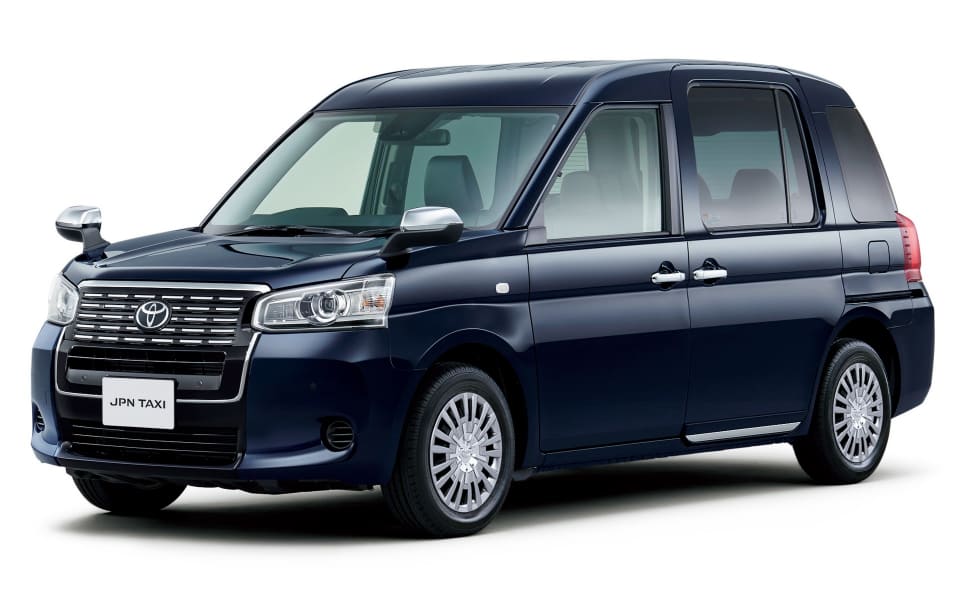 Blue Toyota JPN Taxi minivan photographed from front-left, showing sliding rear doors and passenger windows