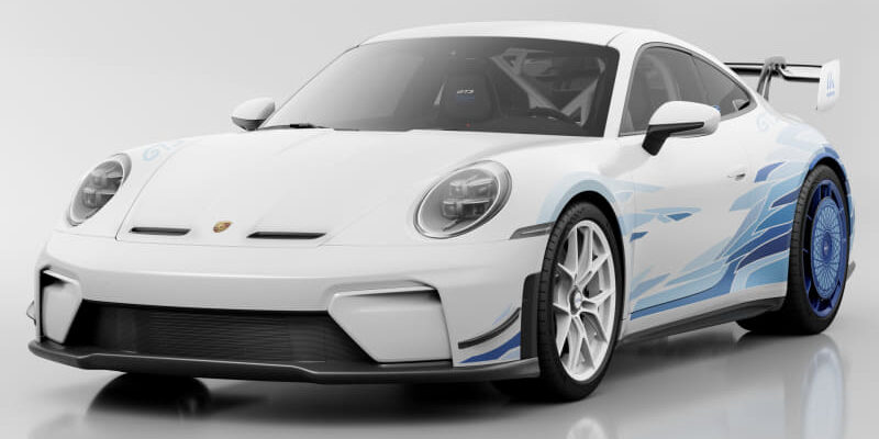 Front three-quarter view of a white Porsche race car with blue graphics and a large rear wing on a glossy surface…