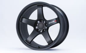 Black five-spoke alloy car wheel with a centered hub and Nismo branding against a light background.
