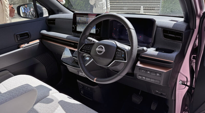 Interior view of a Nissan car cockpit showing steering wheel, dashboard touchscreen, and center console
