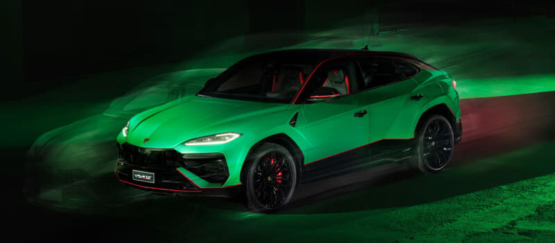 Bright green sports car with red accents driving at night, neon green light trails around it (motion blur).