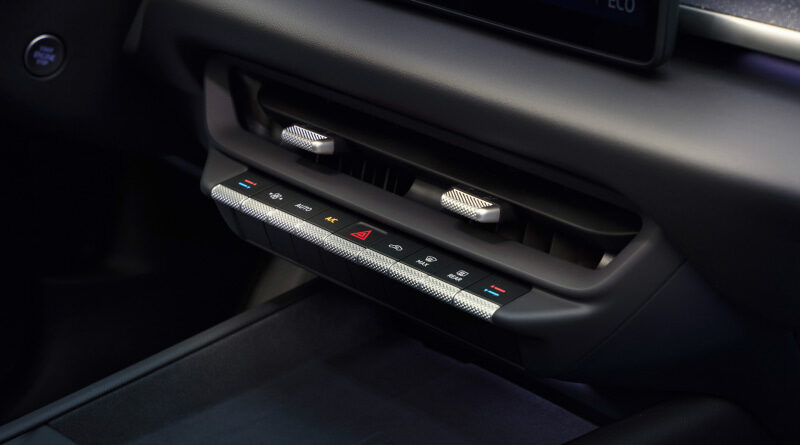 Close-up of a car's center console HVAC controls with air vents and red hazard button, illuminated ambient lighting beneath the buttons.
