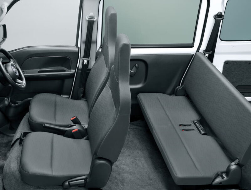 Interior of a grey van showing two front seats and a folded rear bench seat