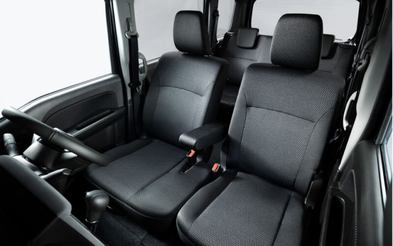 Front seats of a car with black fabric upholstery and a visible steering wheel on the left side.