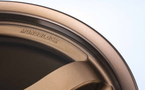 Close-up of a copper-colored disposable coffee cup lid, showing the rim and sipping opening.