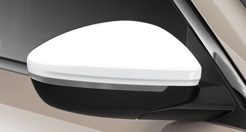 Exterior side mirror on a beige car, white cap with black base visible near the window edge