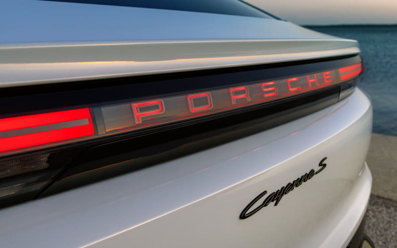 Rear of a white Porsche Carrera S with red backlit PORSCHE lettering on the tail light strip and the Carrera S script badge visible.
