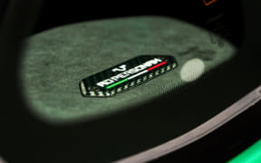 Close-up view through a circular opening of a small rectangular battery resting on a green surface.