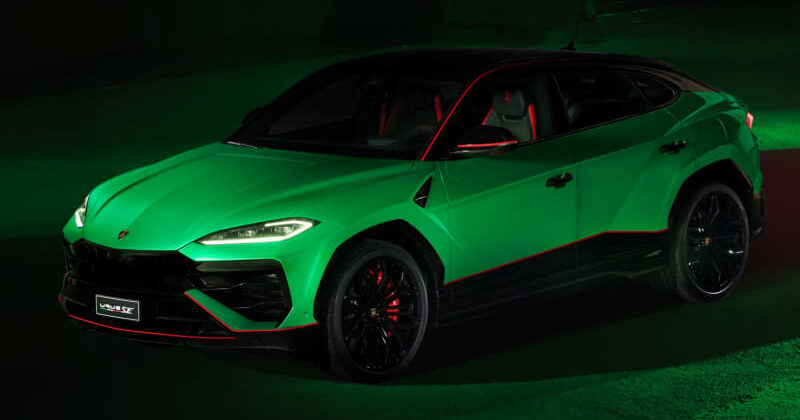 Emerald green Lamborghini Urus with red interior accents under dark showroom lighting.