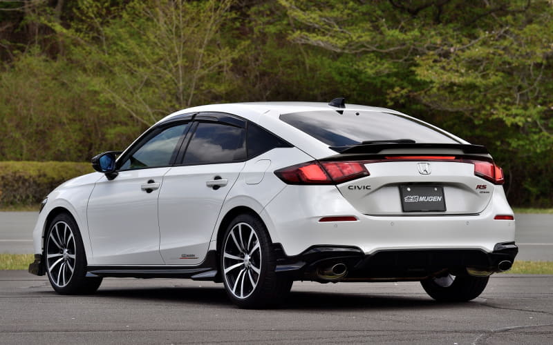 White Honda Civic RS three-quarter rear view parked on an asphalt lot with green trees in the background.