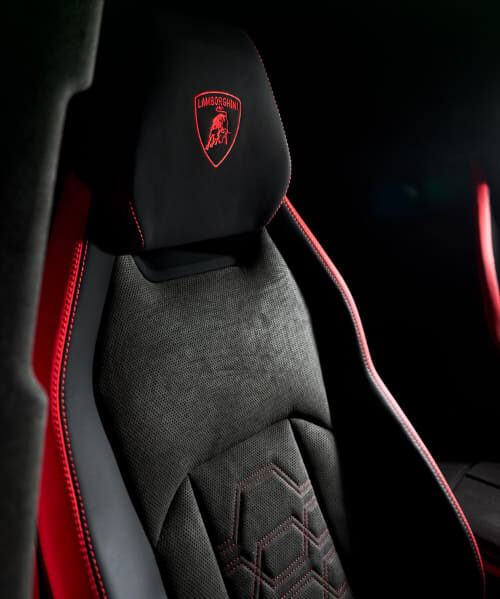 Lamborghini branded car seat with black upholstery and red stitching inside a dark cabin