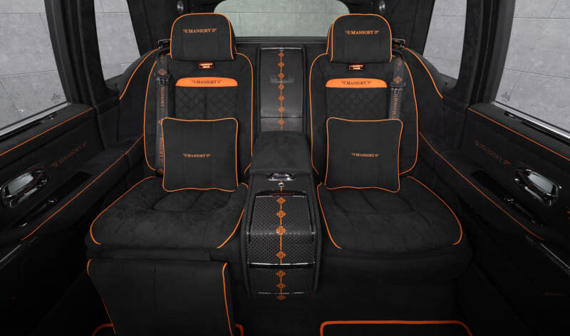 Luxurious black car rear cabin with orange piping and quilted seats labeled Mansory.