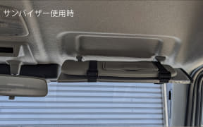 Inside a car, overhead area with sun visors folded down and a strap across them