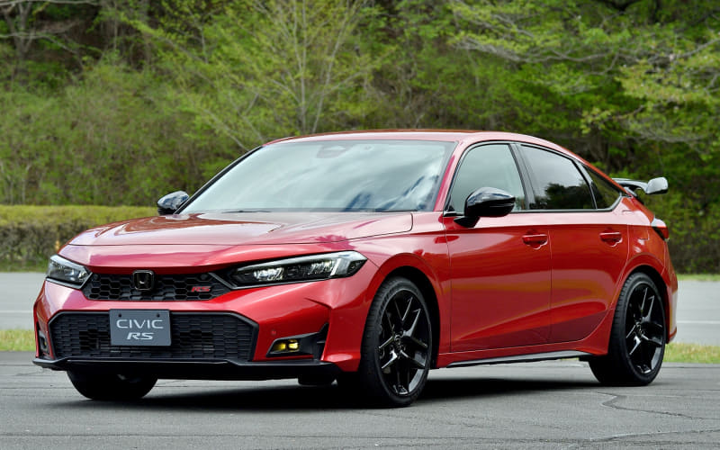 Red Honda Civic RS sedan parked on a paved lot with green trees in the background.