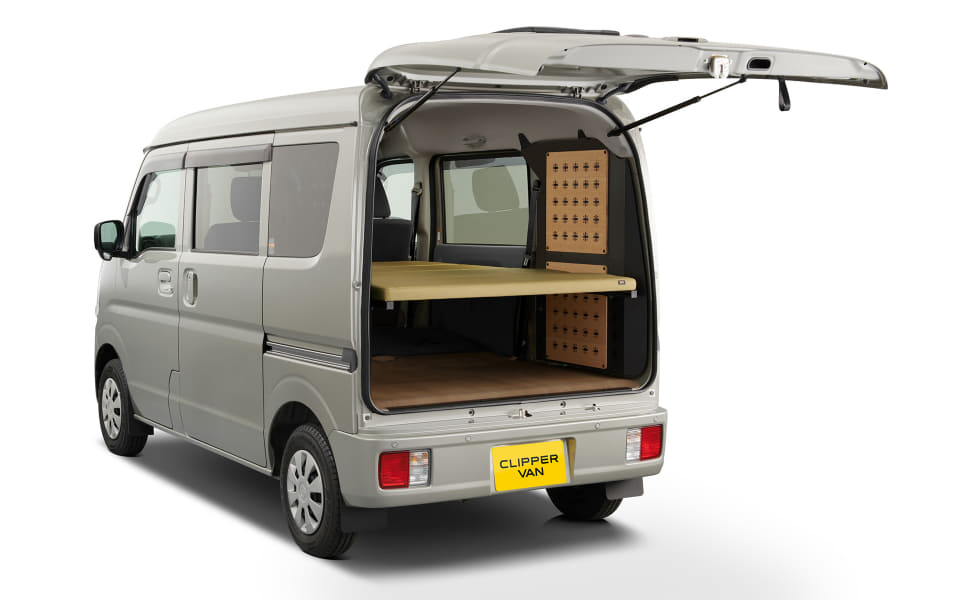 Silver van with rear hatch open, showing a built-in wooden shelf and pegboard storage inside.