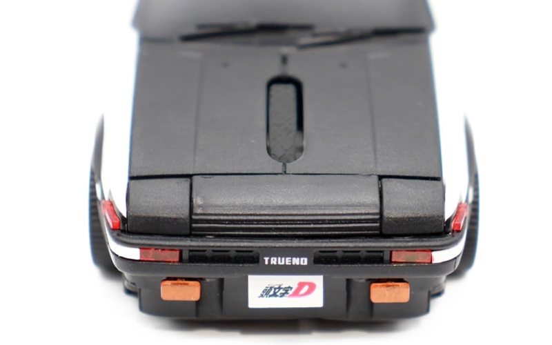 Rear view of a black toy car showing the trunk, taillights, and license plate with Japanese text and a red 'D' emblem.