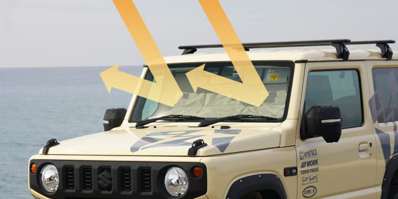 Beige off-road SUV near the ocean with three large orange arrows overlaying the windshield, illustrating wind/airflow toward the vehicle.