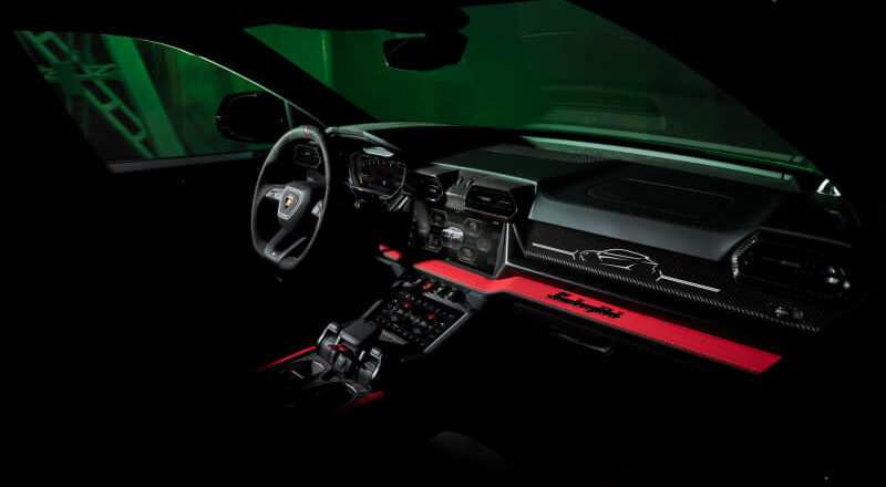 Lamborghini Huracán cockpit: steering wheel, digital gauges, red accents, and carbon-fiber dashboard.