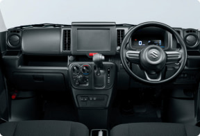 Right-hand-drive car interior viewed from the back seats, showing the steering wheel and central control panel with gear shifter and dashboard displays.