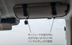 車内の天井に付いたサンシェードを、走行中に広がらないよう2つのバックルで固定している。