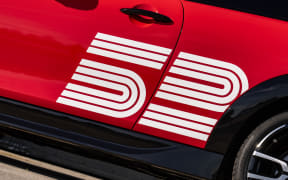 Red car door with a bold white '50' anniversary decal and racing stripes.