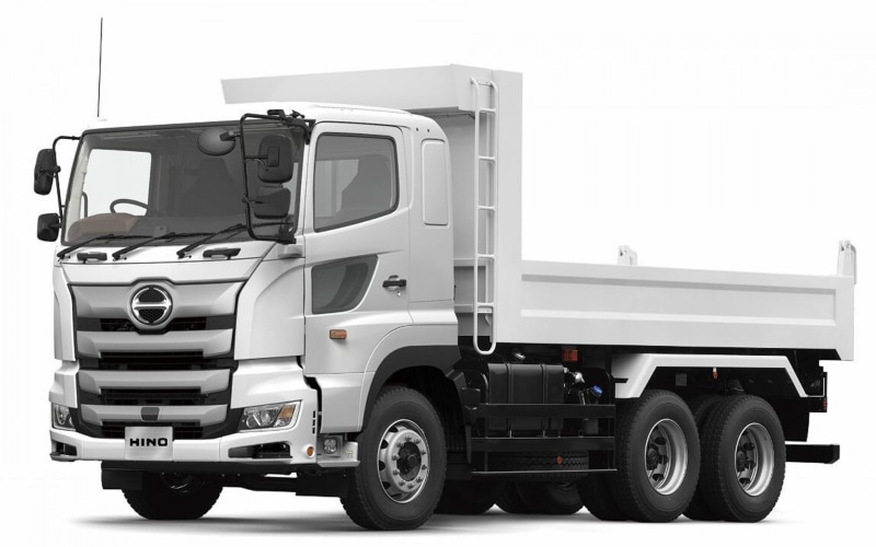 White Hino dump truck, three-axle, shown from a front-side angle with cargo bed ready for loading.