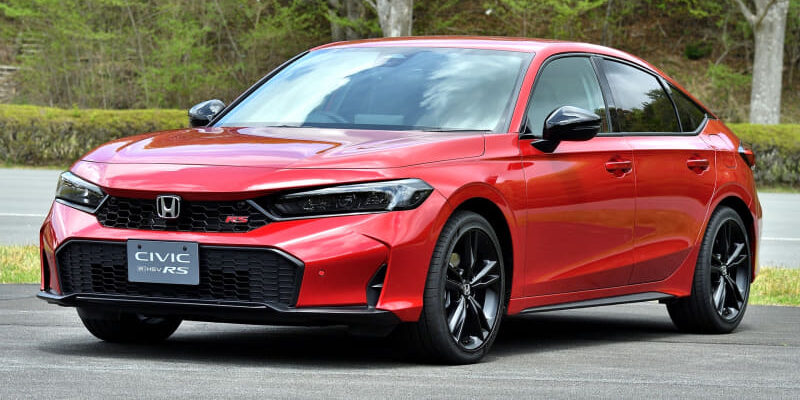 Red Honda Civic RS sedan parked on an asphalt lot with green trees in the background.