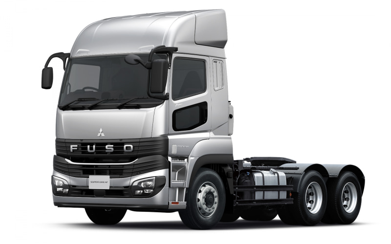 Front three-quarter view of a silver Fuso tractor unit with three rear axles on a white background.