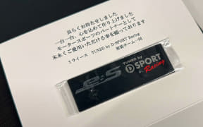 Thank-you card featuring a small black USB flash drive in a clear plastic sleeve on a white surface; note visible in Japanese above the drive.