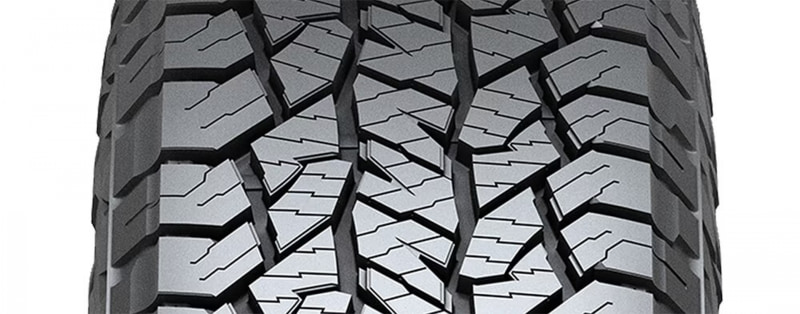 Close-up of rugged off-road tire tread with deep, interlocking blocks and grooves for traction.
