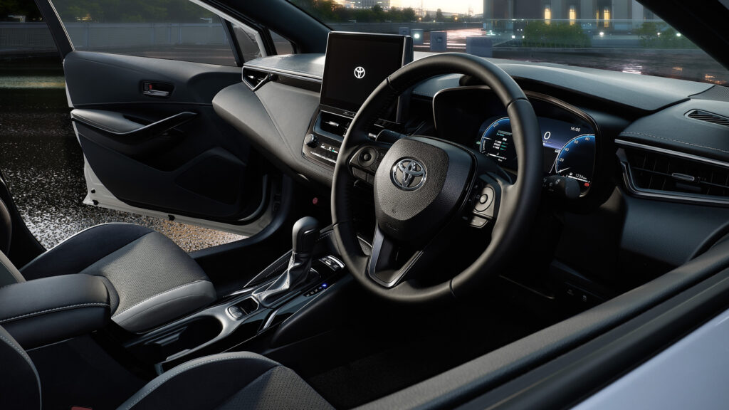 Toyota car interior with a large central touchscreen, digital instrument cluster, and stitched leather seats.