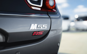 Close-up of a car's rear side with a silver model badge and a red RS emblem.