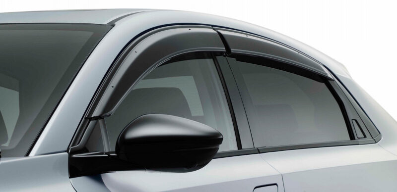 Close-up of a silver car's front side, showing the black side mirror and curved window.