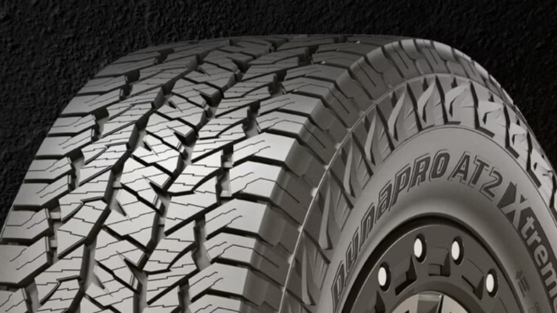 Close-up of an all-terrain tire with deep, aggressive tread patterns mounted on a black rim.