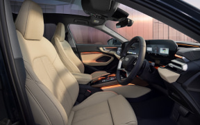 Front interior of a modern sedan with light tan leather seats, steering wheel, and center console