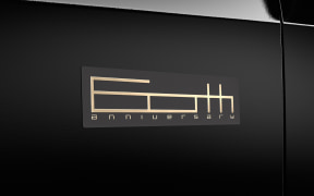 Close-up of a beige badge with stylized lettering on a black car door panel.
