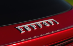 Close-up of the Ferrari script badge on the rear of a red sports car.