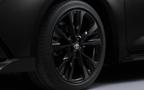 Close-up of a glossy black alloy wheel with many spokes on a dark vehicle, featuring a Toyota emblem at the center.