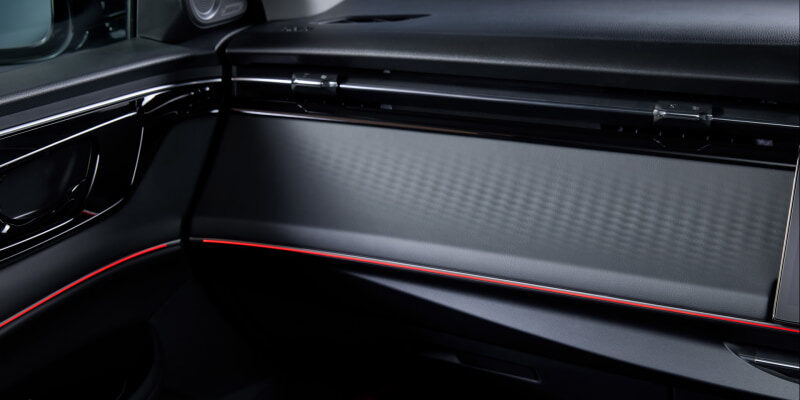 Lux black car interior with a red-illuminated trim running along the dashboard and glove compartment area side panel.