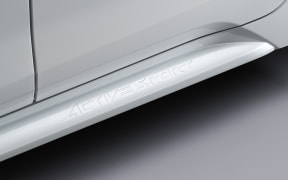 Close-up of a silver SUV's aftermarket running board beneath the door, with 'AFTERMARKET' branding along the edge.