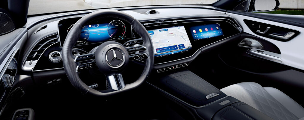 Luxurious car interior with multifunction steering wheel, digital instrument cluster, and large touchscreen infotainment.