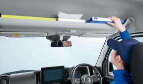 Automotive technician in blue uniform calibrating a windshield ADAS tool from the driver's seat.
