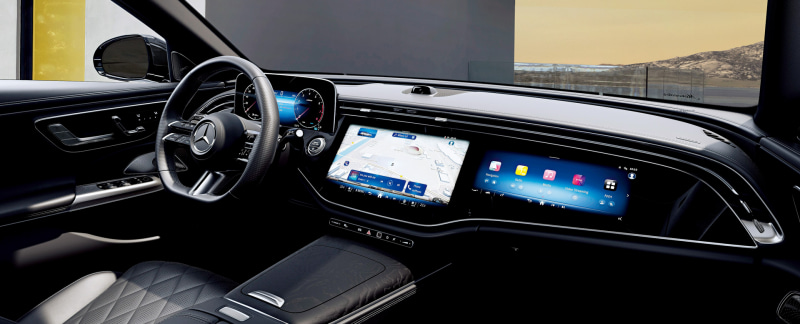 Luxurious car interior with a digital instrument cluster and wide touchscreen displays showing navigation and apps on the dashboard.