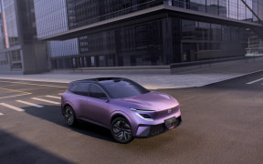 Purple SUV parked on a sunny urban street with modern glass buildings behind.