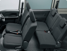 Interior of a car showing front driver and passenger seats and a three-seat rear bench with gray fabric upholstery and visible seat belts, indicating space for five passengers.