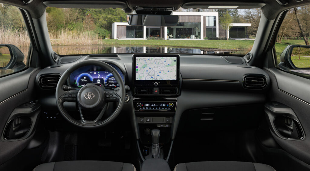 Inside view of a car cabin with a digital instrument cluster, steering wheel, and a center touchscreen map display.
